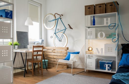 Foto: Zimmer mit Bett, Tisch und Regalen